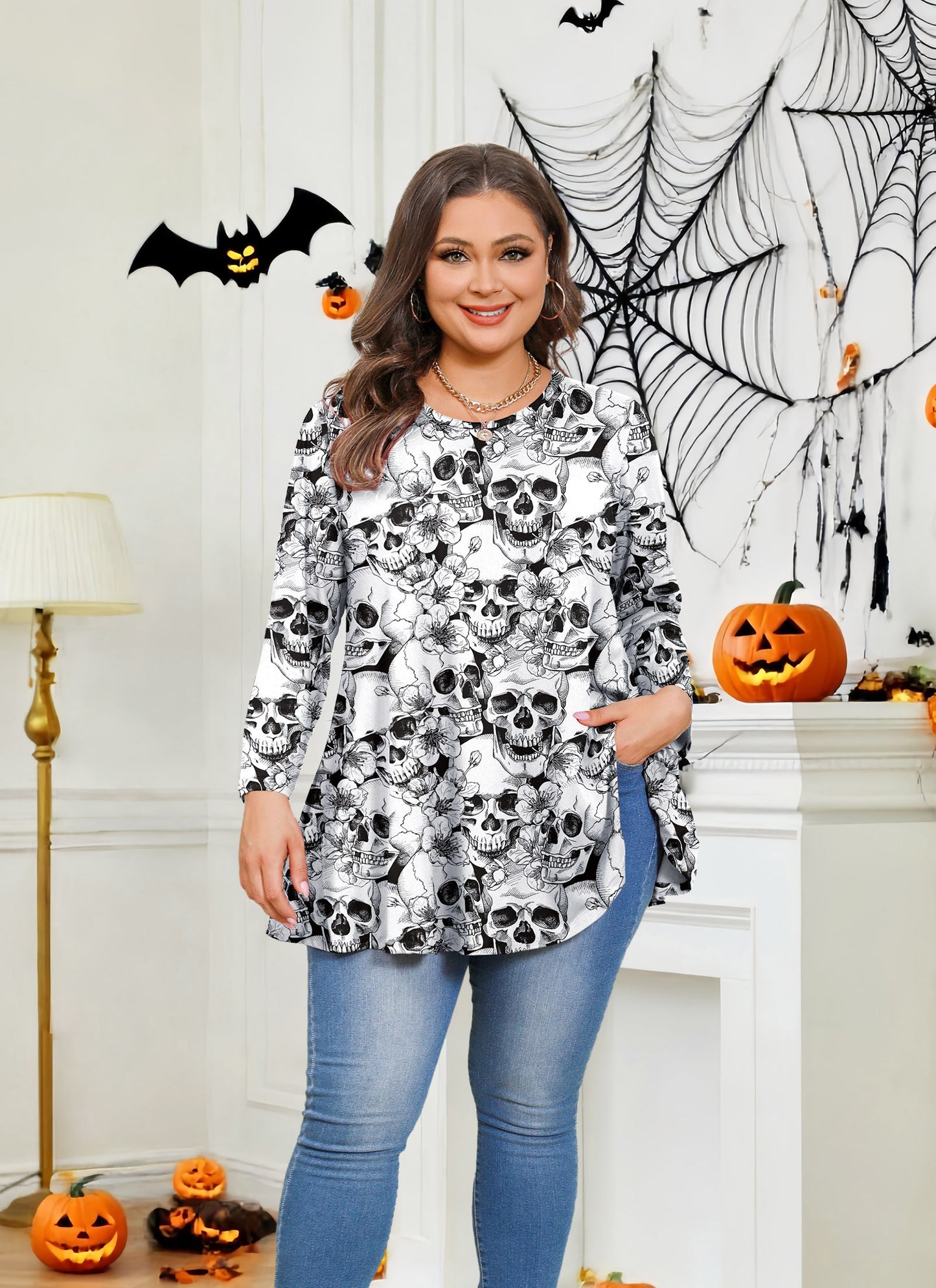 Woman wearing a skull-patterned top in a Halloween-themed room with pumpkins and spider webs.