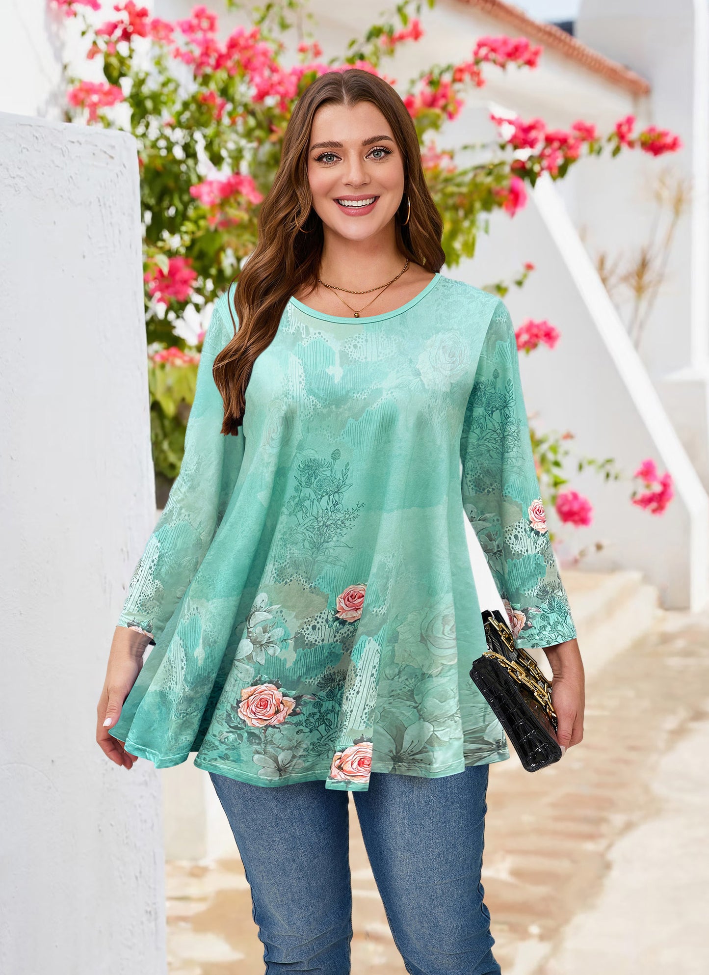 Woman wearing a floral patterned green top with blue jeans, standing in front of a floral background.